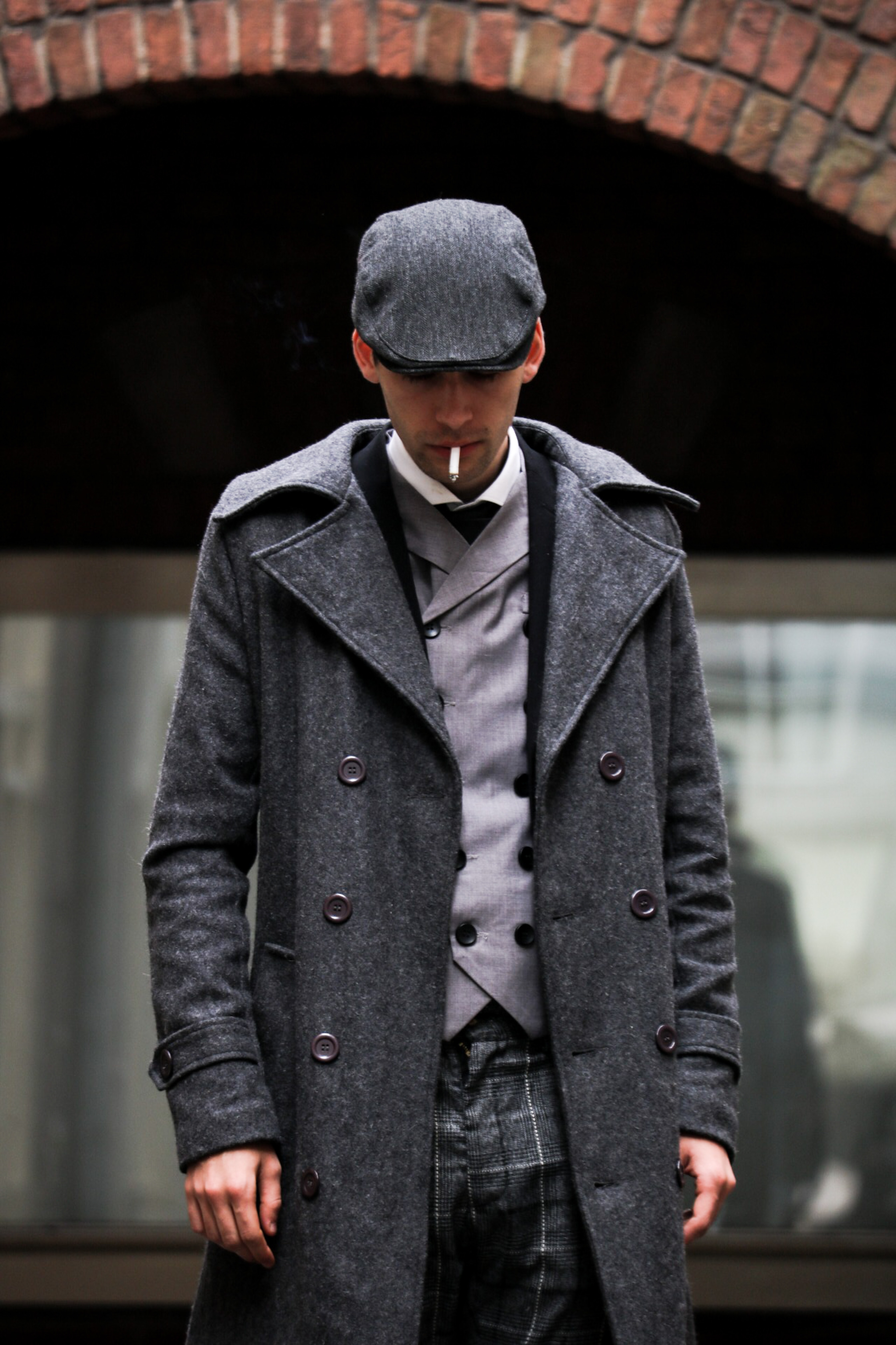 man in grey peacoat smoking cigarette