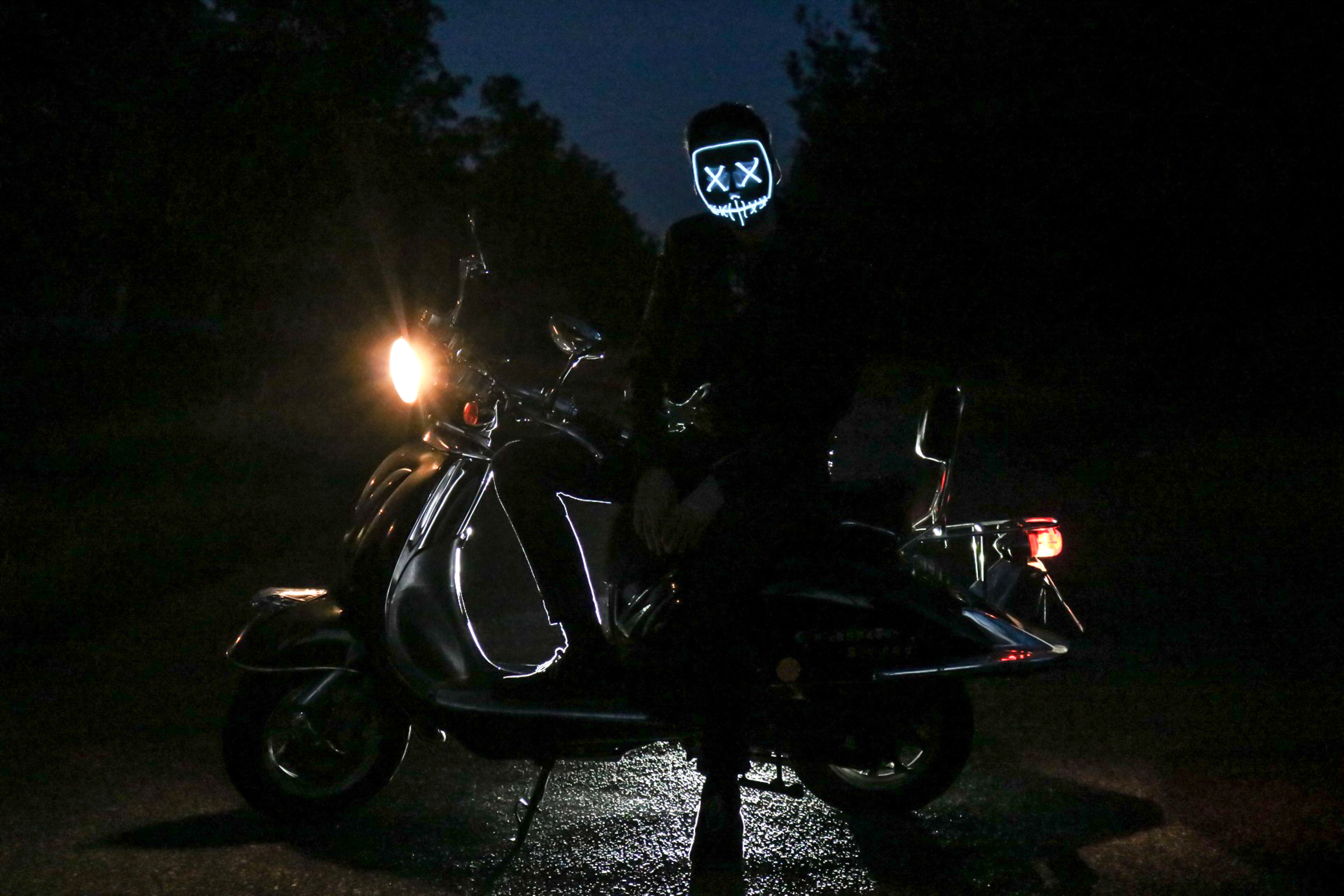man in glowing blue mask sitting on motorcycle